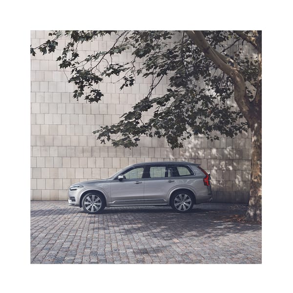 En silvrig volvobil som står i skuggan under ett träd