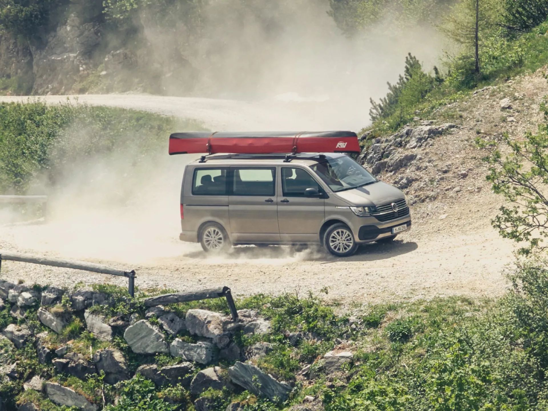 Grå volkswagen transportbil med en kanot på taket