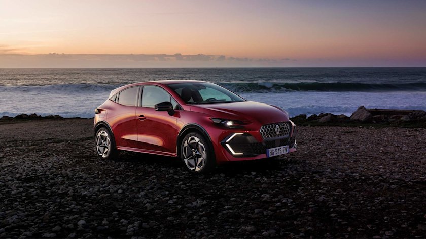 En-röd-sjätte-version-av-Renault-Clio-står-parkerad-framför-havet-under-solnedgång